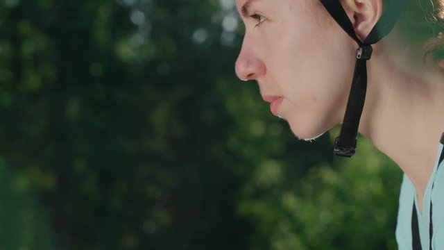 Side view of face of confident female cyclist in protective helmet looking up with determination