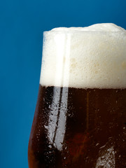 A glass of beer with a close-up on a blue background.