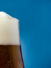 A glass of beer with a close-up on a blue background.