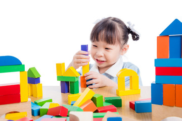 Little asian kinderkarten girl playing colorful wood block over white background