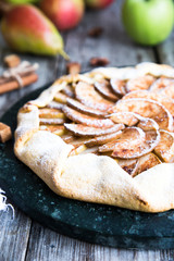 Pie with apples, pears and cinnamon on an old wooden background