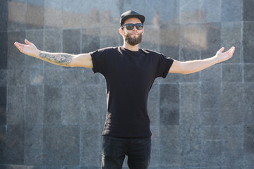 Hipster handsome male model with beard  wearing black blank t-shirt with space for your logo or design in casual urban style