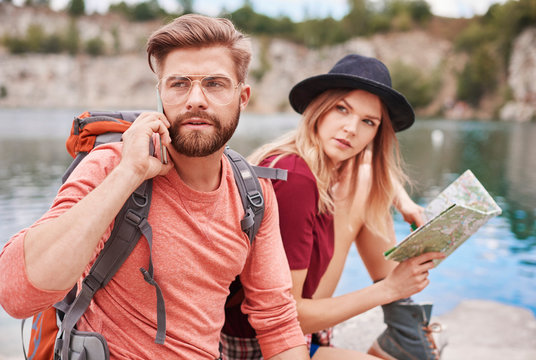 Couple with map using cellular phone, Krakow, Malopolskie, Poland, Europe