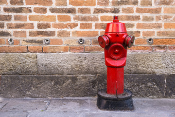 Red fire hydrant on the street on the brick wall background