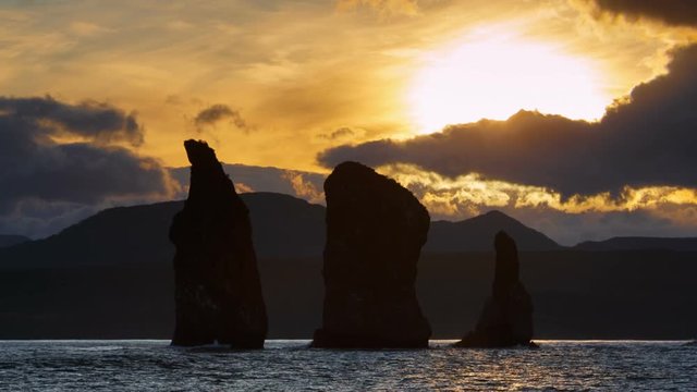 Kamchatka Peninsula seascape: rocky islands in sea at sunset - beautiful view of Three Brothers Rocks in Avacha Bay (Avachinskaya Bay) in Pacific Ocean. Eurasia, Russian Far East, Kamchatka Region.