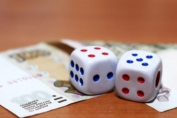 Two dice laying over a pile of money