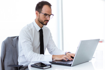 Handsome young man working with laptop in the office.