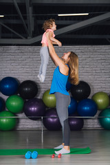 Mother and baby girl do exercises together in the gym