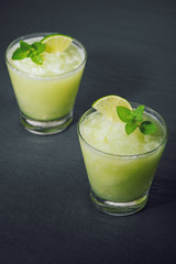 Cocktail juice with lime, mint and ice. Bar drink accessories on black table background.
