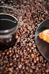 Croissant and coffee beans in close up photo. Delicious morning drink and snack