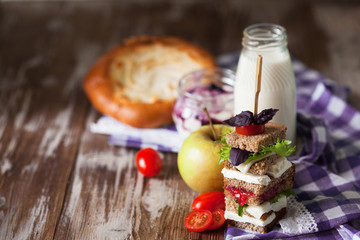 Healthy school lunch with a sandwich, fresh fruits, bun and milk