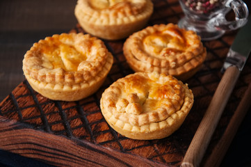 Mini meat pies from flaky dough on a vintage tray over wooden background. - 175470343
