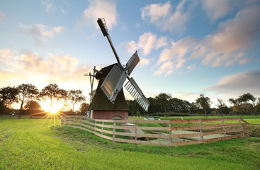 Fototapeta na wymiar sunrise behind charming Dutch windmill