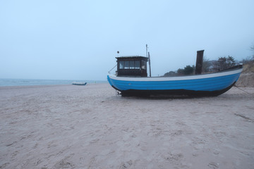 Naklejka premium Fischerboot am Strand im Nebel