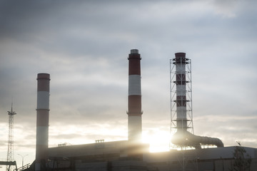 Three pipes in the city with smoke.