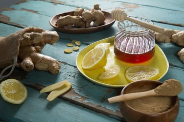 Lemon and ginger with honey jar on weathered table
