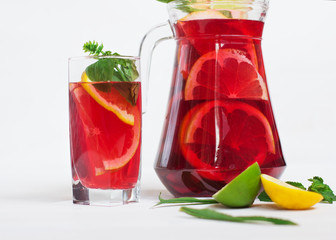 tasty and juicy sangria with citrus in a glass next to the pitcher on a white background.