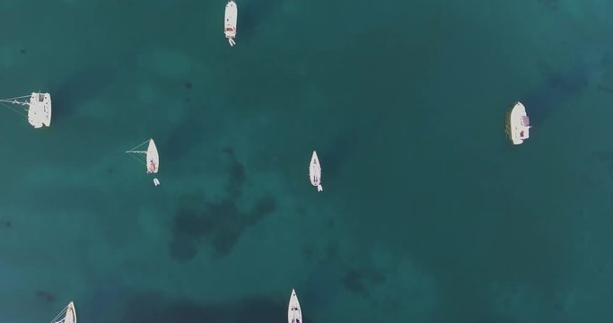 Aerial, beautiful bay with some anchored boats and yachts and crystalline water on sunrise