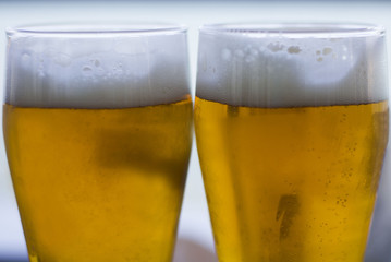 Two glasses of beers on a wooden table.