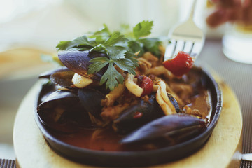 Hand holding a fork and a mussel; restaurant setting