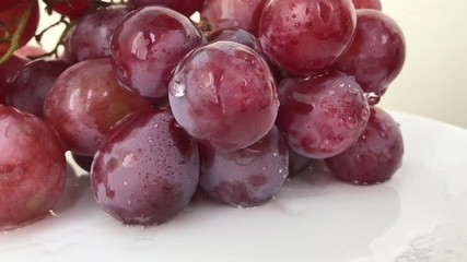 Slow motion: Fresh bunch of black wine grapes with water drops rotate on white background. A lot Red Grapes White background wet water droplet, authentic motion rain water droplets natural fruti lamp - Powered by Adobe