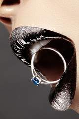 Close-up of beautiful woman's Lips with bright Fashion Make-up. Macro glitter lip gloss. Luxury Jewelry accessorie