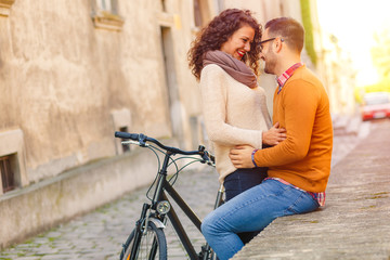 Happy young couple with a bicycle on sunny autumn day in the city.