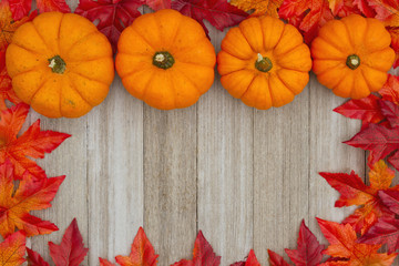 Autumn background with pumpkins and fall leaves on weathered wood