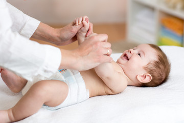 Fototapeta na wymiar Baby massage. Massagist massaging and doing gymnastic to little kid