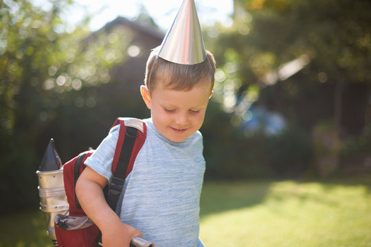 Happy boy in rocket costume and backpack in garden