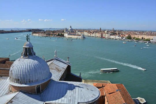 The view from the top of the bellltower of San Giorgio Maggiore, Venice. The church's roof is in the foreground with Punta Della Dogana & Santa Maria Della Salute in the background
