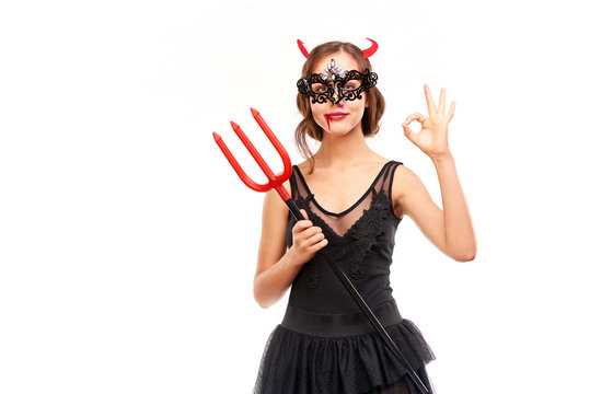 Portrait of beautiful she-devil posing with trident on Halloween against white background