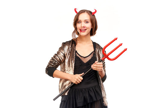 Portrait of beautiful she-devil posing with trident on Halloween against white background