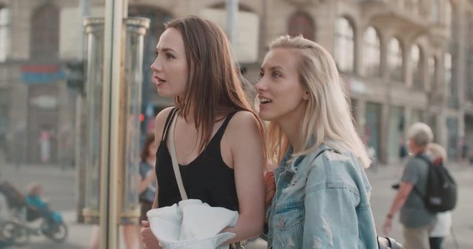 Two beautiful girls looking at clothes in a shop window. Teenage girls shopping together in a city. 
