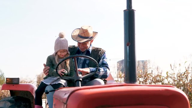 Interested girl watching a tractor with grandfather 