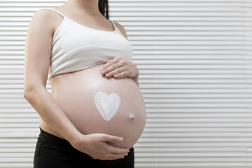 Pregnant woman applying cream on her belly