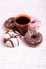 Different type of donuts on white wooden background next to a glass of cola. Delicious junk food
