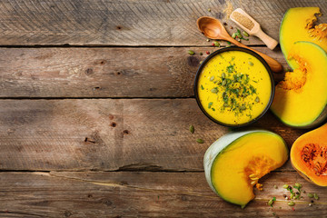 Obraz na płótnie Canvas Vegetable and lentils creamy soup, cut pumpkin, seeds, parsley on rustic wooden background. Top view, copy space