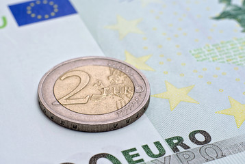 Coin two euros  on the banknote of hundred euro