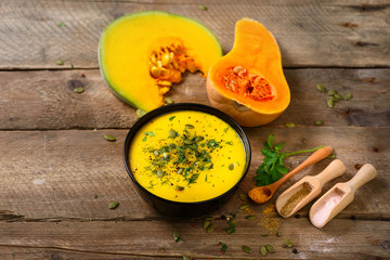 Vegetable and lentils creamy soup, cut pumpkin, seeds, parsley on rustic wooden background. Top view, copy space