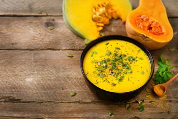 Vegetable and lentils creamy soup, cut pumpkin, seeds, parsley on rustic wooden background. Top view, copy space