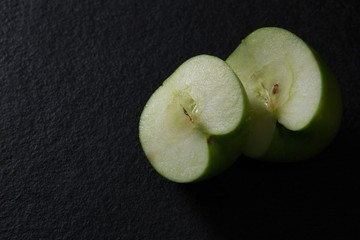 Halved green apple on black background