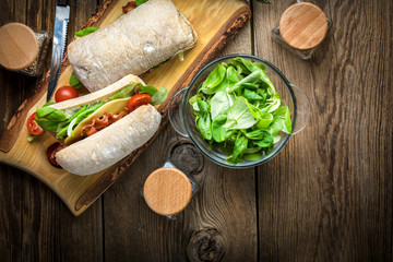 Ciabatta sandwich with arugula salad, bacon and yellow cheese.