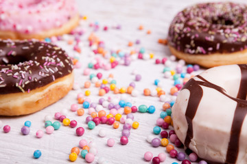 Close up of Different type of donuts in and sweet candy on white wooden background. Delicious junk food