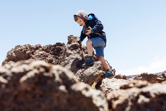 Boy clambering up rocks at Mount Teide, Tenerife, Canary Islands