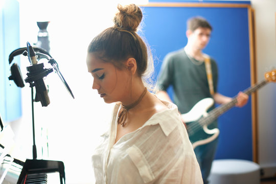 Young female college student preparing to sing in recording studio
