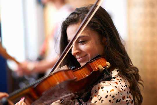 Young female college student playing violin in recording studio