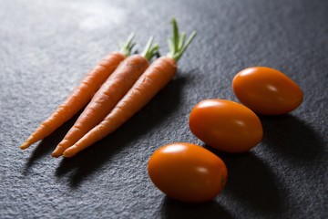 Carrots and tomatoes on black background