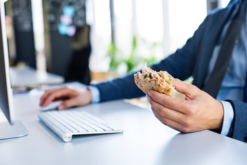 Businessman at the desk with computer eating lunch.