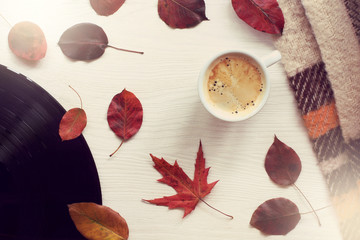 warming music of autumn/ mug with coffee, leaves, vinyl plate on a light table top view